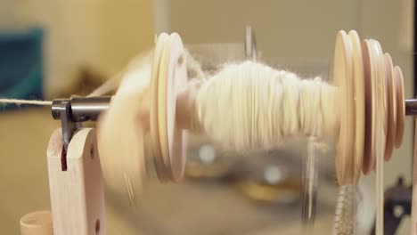 Fibre-art-close-up:-Grey-wool-spun-into-yarn-on-spinning-wheel-bobbin