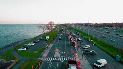 Aerial-view-of-red-semi-truck-driver-driving-trough-Food-Truck-Paradise-in-New-Haven,-Connecticut,-USA-at-sunset