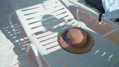 Woman-shadow-and-a-straw-hat-thrown-on-a-beach-bench