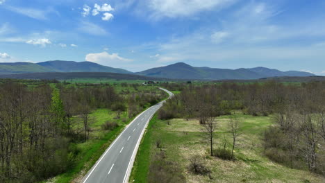 Aerial-shot-of-a-road-that-stretches-across-a-mountain-plateau-overgrown-with-grass-and-groves