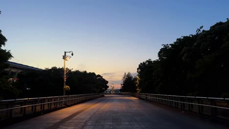 Das-Licht-Des-Frühen-Morgens-Taucht-Eine-Leere-Parkbrücke-In-Bäume-Und-Einen-Warmen-Himmel