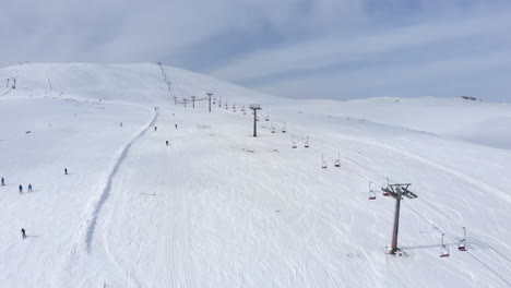 Drone-view-of-skiers-skiing-downhill-in-the-slopes-in-the-scenic-Mountain-Kaimaktsalan-Greece-winter-day