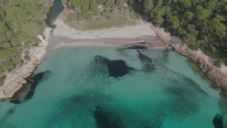 Blue-sea-bay-in-Cala-Trebaluger-Menorca-beach,-summer-in-Spain-travel-aerial-drone-shot