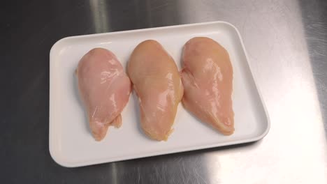 Close-up-of-fresh-chicken-fillets-lying-on-a-tray,-ready-for-further-processing