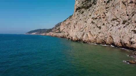 Rocky-garraf-coast-under-the-bright-sun,-showcasing-the-serene-mediterranean-waters,-aerial-view