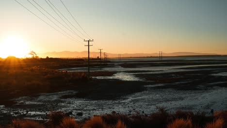 Panorama-Sonnenuntergang-Zeitraffer-Im-Feuchtgebiet-Neuseelands-Mit-Strommasten-Und-Schornsteinen