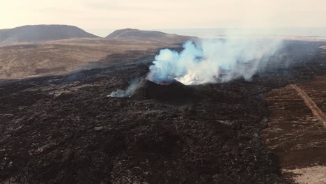 Ausbrechender-Vulkan-Grindavík-Mit-Rauchendem-Krater-In-Karger-Landschaft