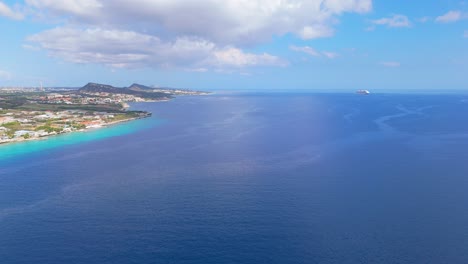 Crucero-En-El-Horizonte-Con-Penachos-Actuales-Frente-A-La-Costa-De-Willemstad-Curazao,-Aéreo