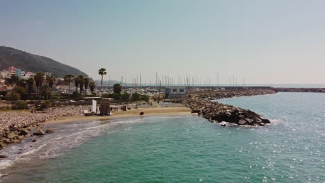 Costa-De-Garraf-En-Barcelona,-Día-Soleado-Con-Aguas-Cristalinas-Y-Barcos-Atracados-En-El-Puerto-Deportivo,-Vista-Aérea