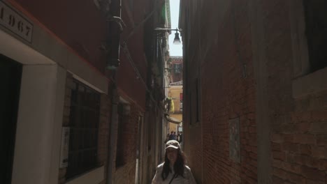 Una-Mujer-Camina-Por-Las-Típicas-Calles-Estrechas-Del-Casco-Antiguo-De-Venecia,-Italia.