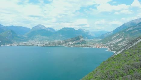 Lake-Garda-seen-from-above,-captivating-drone-aerial-shot,-highlighting-the-lush-green-vegetation,-inviting-hiking-trails,-and-majestic-mountains-of-the-Veneto-region-in-Italy