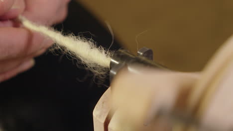 Closeup:-Grey-wool-twists-into-natural-yarn-in-spinning-wheel-bobbin