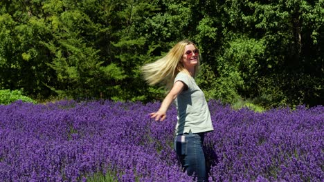 Happy-blond-woman-spinning-around-in-a-purple-lavander-field-in-New-Zealand