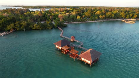 Aerial-orbiting-overwater-villas-at-sunrise-in-a-tropical-landscape-in-Leebong-Island-Indonesia