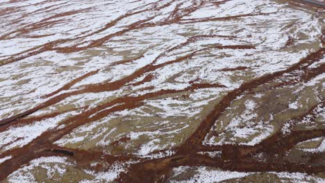 Streaks-of-brown-land-created-by-dried-up-rivers-in-snowy-glacier-plain