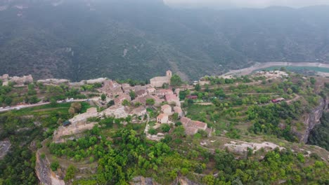 Siurana-town-surrounded-by-lush-landscapes-and-a-river,-daylight,-aerial-view