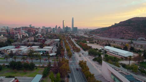 Drone-dolly-in-estrablishing-shot-of-the-skyline-of-Santiago-Chile-with-an-orange-sunset-at-the-Bicentennial-Park-of-Vitacura