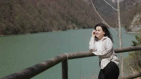 Mujer-Posando-En-La-Valla-Con-Montañas-Y-Lago-Al-Fondo