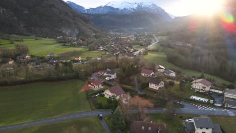 Amanecer-Sobre-Un-Pequeño-Pueblo-Rodeado-De-Hierba-Verde-Y-Montañas