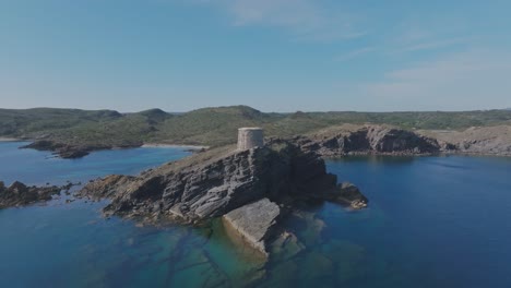 D'es-Colomar-Stone-Tower-Beach-Cliff-Landscape-in-Coastal-Menorca-Spain-Travel-Destination,-Drone-Panoramic