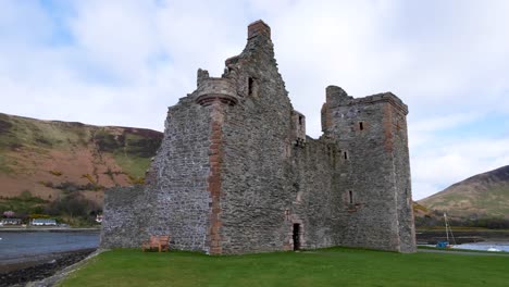 Exterior-view-of-historical-Lochranza-Castle-landmark-with-ocean-and-mountains-on-Isle-of-Arran-in-Western-Scotland-UK