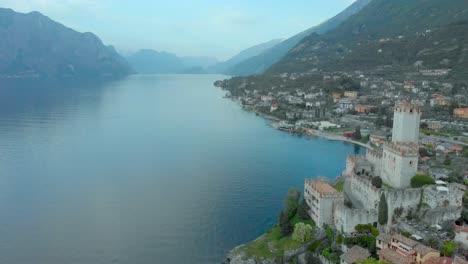 Luftaufnahme-Des-Burgturms-Von-Malcesine-Mit-Blick-Auf-Den-Gardasee,-Die-Stadt,-Die-Dächer-Und-Die-Berge,-Italien