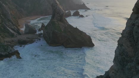 Aerial-revealing-shot-of-Ursa-Beach-in-Portugal-with-reaching-waves-between-rocks-and-cliffs