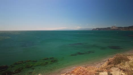 Crimea,-Cabo-Megan,-Surfistas-Con-Una-Vela-Cortan-Las-Aguas-Verdes-Del-Mar-Negro-En-Primavera-Cálida