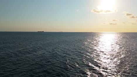 Large-vessel-ships-on-ocean-horizon-as-water-sparkles-from-sunlight,-aerial