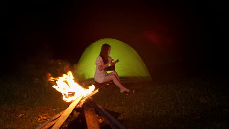 woman-chatting-outdoor-in-front-of-bonfire-while-camping-at-night-in-remote-destination