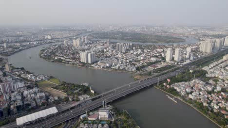 Ho-Chi-Minh,-Saigon,-Vietnam,-Mit-Dem-Fluss,-Der-Zwischen-Den-Wohngebieten-Und-Einer-Brücke-Fließt,-Luftbild-Drohnenvideo-Bei-Sonnenuntergang