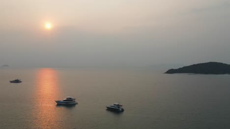 Luftaufnahme-Von-Yachten,-Die-In-Den-Gewässern-Vor-Dem-Strand-Von-Ao-Suan-Yai-Vor-Anker-Liegen,-Mit-Goldorangefarbenem-Sonnenuntergang-über-Dem-Horizont