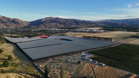Large-greenhouse-plantation-in-beautiful-New-Zealand-mountain-panorama,-drone