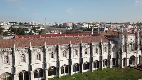 Lisbon,-Belem,-Jeronimos-Monastery's-drone-footage-starting-from-the-left-side-of-the-building-and-camera-slides-towards-to-the-tower-and-zooming-in-while-the-bridge-also-can-be-seen