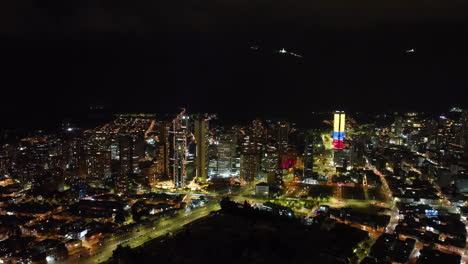 Aerial-tracking-shot-of-night-lit-skyscrapers-in-downtown-of-Bogota,-Colombia