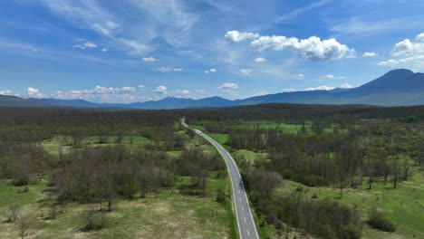 Luftaufnahme-Einer-Straße,-Die-Sich-über-Ein-Mit-Gras-Und-Hainen-Bewachsenes-Bergplateau-Erstreckt