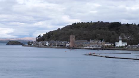 Overlooking-Oban-bay-towards-waterfront-with-houses,-hotels,-and-church-in-popular-tourism-destination-of-Western-Scotland-UK