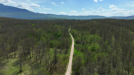 Luftaufnahme-Einer-Unbefestigten-Straße,-Die-Sich-über-Ein-Mit-Gras-Und-Hainen-Bewachsenes-Bergplateau-Erstreckt