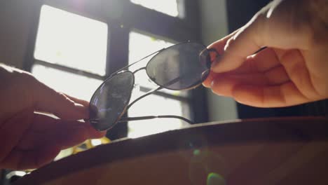 Gafas-De-Sol-Con-El-Telón-De-Fondo-De-La-Luz-Del-Sol-Que-Entra-A-Través-De-Una-Ventana-De-Madera