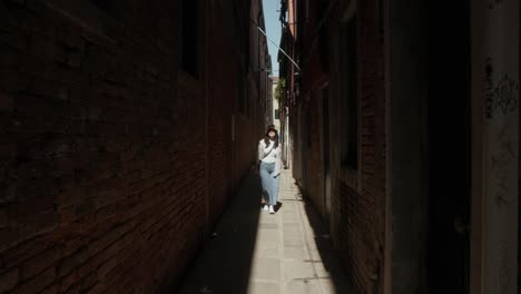 Retrato-De-Una-Mujer-Caminando-Por-El-Callejón-Con-Edificios-De-Paredes-De-Ladrillo-En-Venecia,-Italia