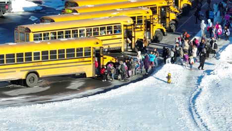 Grundschüler-Besteigen-Gelbe-Schulbusse,-Um-An-Einem-Schneetag-Nach-Hause-Zu-Fahren,-Vorzeitiger-Schulschluss,-Zweistündige-Verspätung