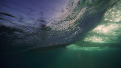 Panorámica-Submarina-Hasta-Surfista-En-Longboard-De-Una-Sola-Aleta-Mientras-La-Ola-Rompe