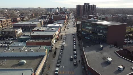 Drones-Vuelan-Sobre-La-Calle-Principal-En-Saint-lambert,-Quebec,-Canadá,-Con-Tráfico-De-Automóviles-Conduciendo-Durante-Un-Día-Soleado