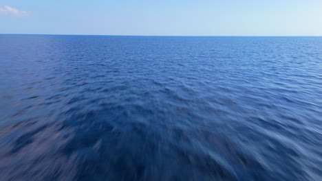 Aerial-pullback-above-calm-ocean-water-surface-texture-with-horizon-in-distance