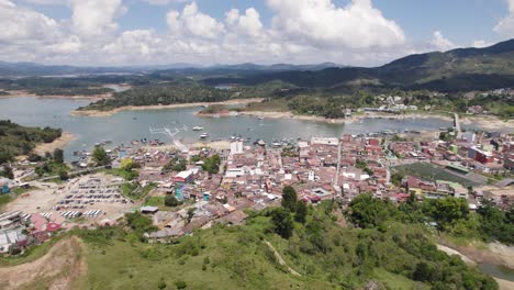Small-town-Guatapé-on-reservoir-del-Peñol-in-Colombia,-aerial-orbit-sunny-day
