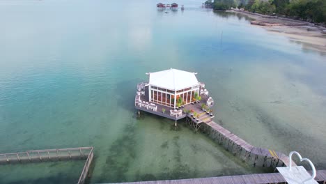 Aerial-shot-of-a-floating-restaurant-with-a-wooden-pier-in-the-middle-of-the-sea