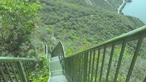 Lake-Garda-railing-reveals-Busatte-Tempesta-pathway-with-metal-railing,-sky,-water,-waves,-mountains,-and-clouds