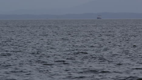 Coastal-water-surface-with-boat-out-of-focus-on-hazy-mountain-backdrop