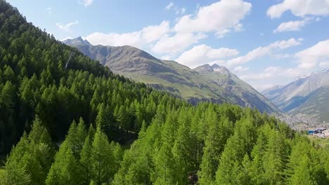 Vuelo-Sobre-Un-Bosque-En-Las-Hermosas-Montañas-De-Los-Alpes-Suizos-Con-La-Ciudad-De-Zermatt-Al-Fondo