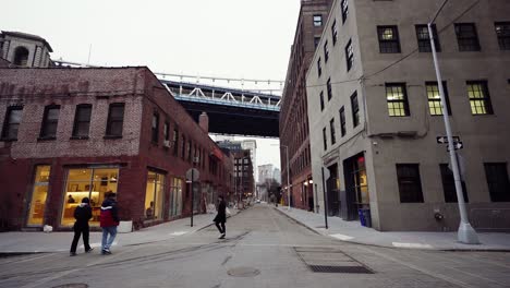 Brooklyn-Dumbo-Street-People-Walking-With-Manhattan-Bridge-And-Brooklyn-Bridge-Behind-Buildings